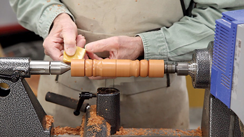 Spreading carnauba wax brick on spindle turning