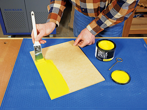 Spreading milk paint on a wood panel