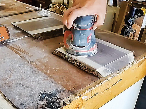 Sanding down a slab of walnut lumber