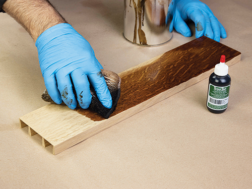 Rubbing brown dye on serving table drawer side